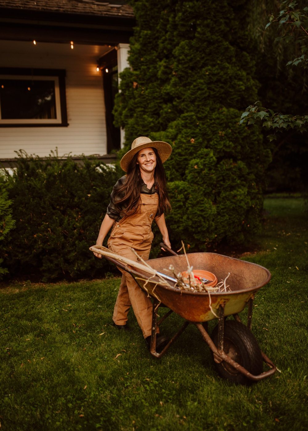 Jenna, the owner, pushing a wheelbarrow across a front lawn